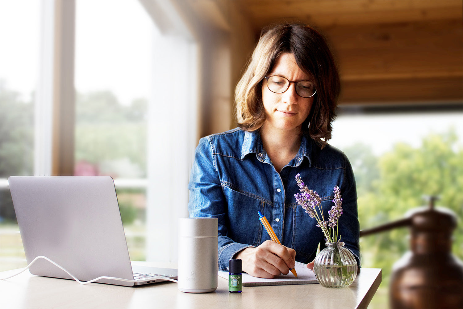 Frau am Schreibtisch mit Laptop, Stift und Papier